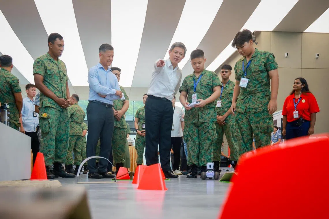 Minister for Defence Chan Chun Sing (centre) viewing land surveillance robots with NCC cadets from Peirce Secondary, on Aug 26.