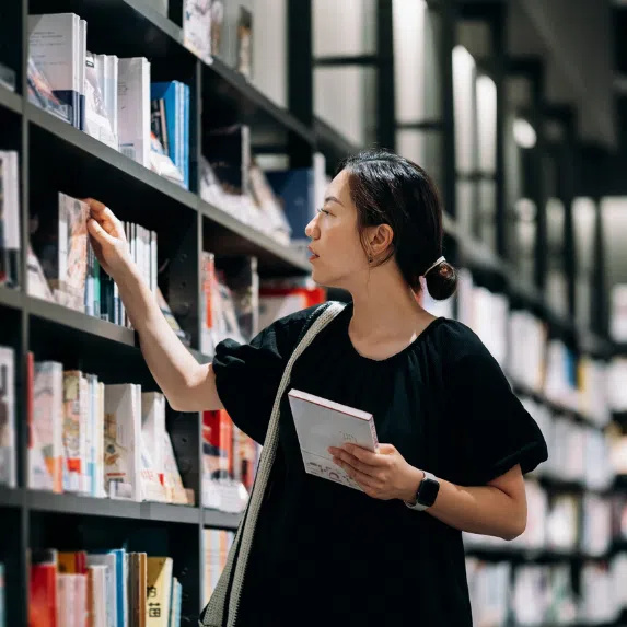 Where to buy SingLit books in Singapore: Chinese woman selecting books from shelf