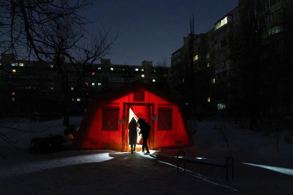 People enter a tent provided by emergency services for residents whose apartments are left without heating during sub-zero temperatures, amid Russia's attack on Ukraine, during a winter night in Kyiv, Ukraine January 17, 2026. REUTERS/Thomas Peter