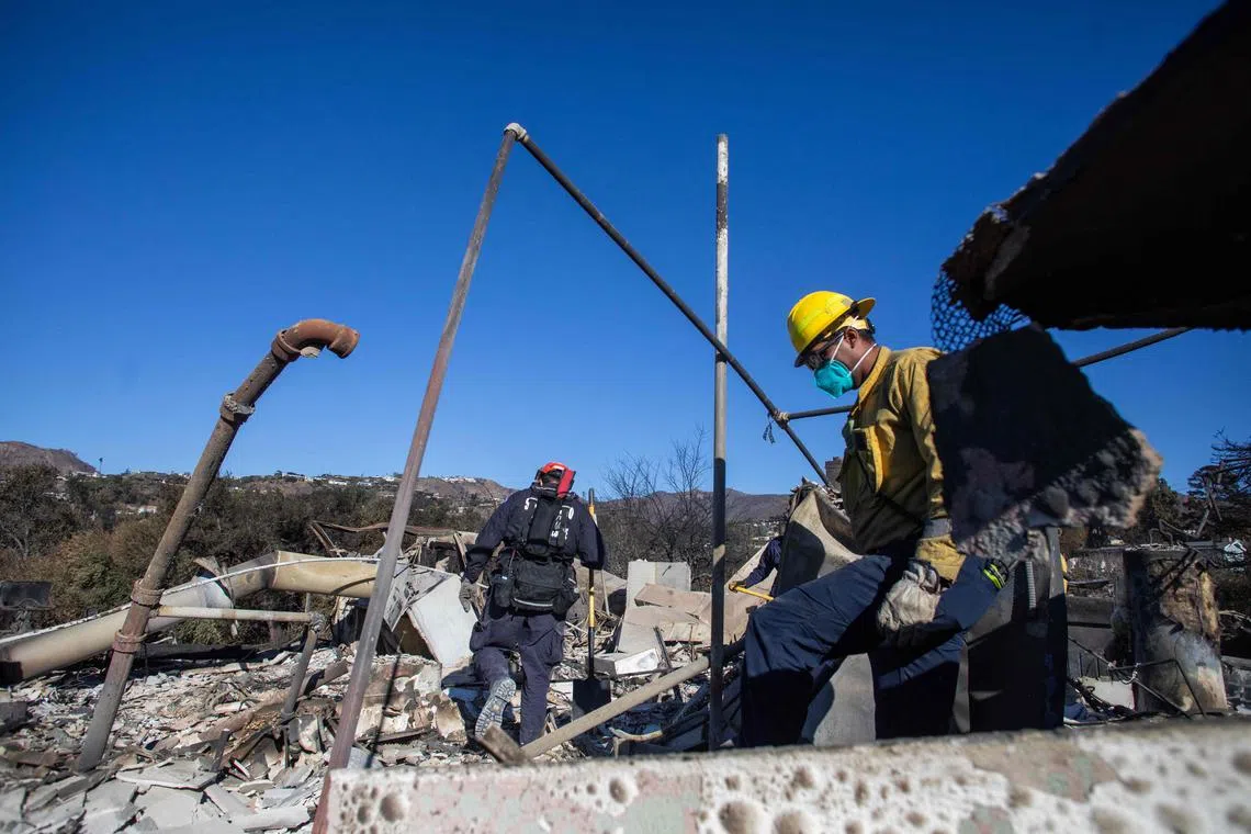 Los Angeles firefighters inspect a burned house from the Palisades fire in the Pacific Palisades neighbourhood.