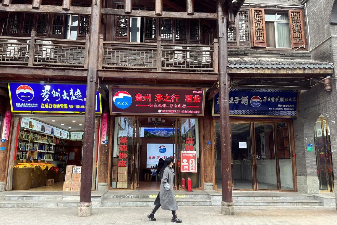 A woman walks past liquor stores in Maotai, Guizhou province, China December 30, 2024. REUTERS/Casey Hall