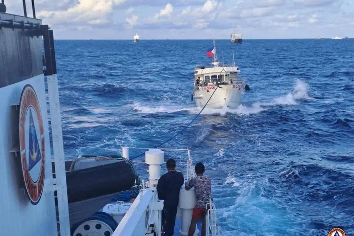 FILE PHOTO: A Philippine Coast Guard ship tows a Filipino resupply vessel following damages due to water cannon from a Chinese Coast Guard ship as it was heading towards the disputed Second Thomas Shoal, in the South China Sea, December 10, 2023. Philippine Coast Guard/Handout via REUTERS