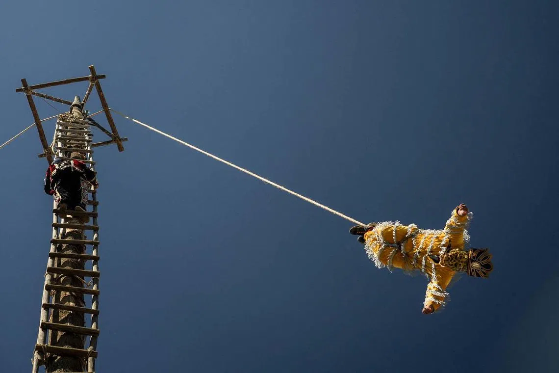 An Indigenous man performs the Flying Pole outside Santo Tomas church in Chichicastenango, Guatemala, on December 20, 2023. Palo Volador (flying pole) is an indigenous-pre-Hispanic tradition in Guatemala in which people climb to the top of a 30-meter trunk to thank for the crops and welcome the winter solstice. (Photo by Emmanuel Andres / AFP)