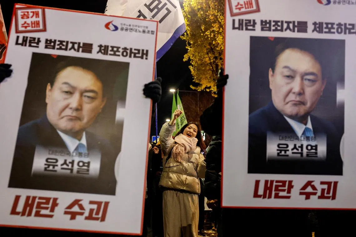 Protesters hold placards during a candlelight vigil to condemn South Korean President Yoon Suk Yeol's surprise declaration of the failed martial law.