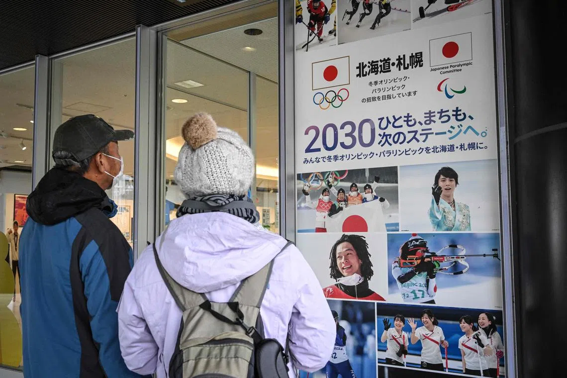 This picture taken on Nov 20, 2022 shows people looking at a poster promoting Sapporo city's candidacy to host the 2030 Winter Olympics and Paralympics at the Sapporo Olympic Museum in Sapporo.