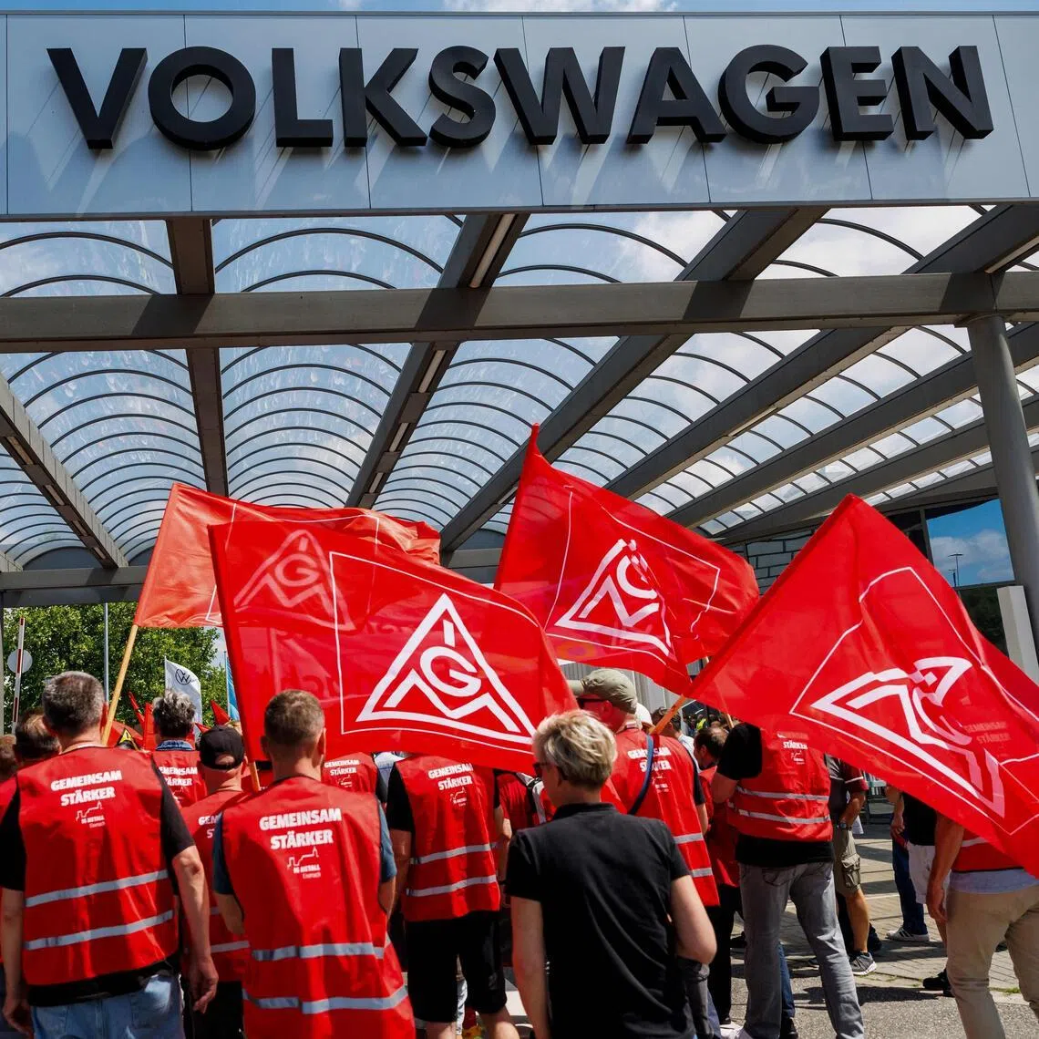(FILES) Employees of German car maker Volkswagen (VW) carry flags of German trade union IG Metall as they take part in a rally to protest against restructuring and mass job cut plans at the VW plant in Zwickau, eastern Germany on July 9, 2026. Volkswagen's boss told employees on July 13, 2026 a further 50,000 jobs could go at the struggling auto giant, according to an internal memo seen by AFP, confirming reports the group is targeting 100,000 cuts worldwide. (Photo by Jens SCHLÜTER / AFP)
