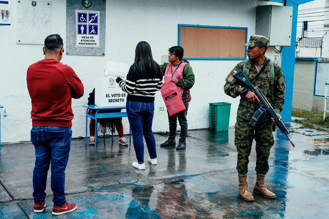 A member of the military stands guard as voters cast ballots at a polling station Ecuador's capital, Quito.