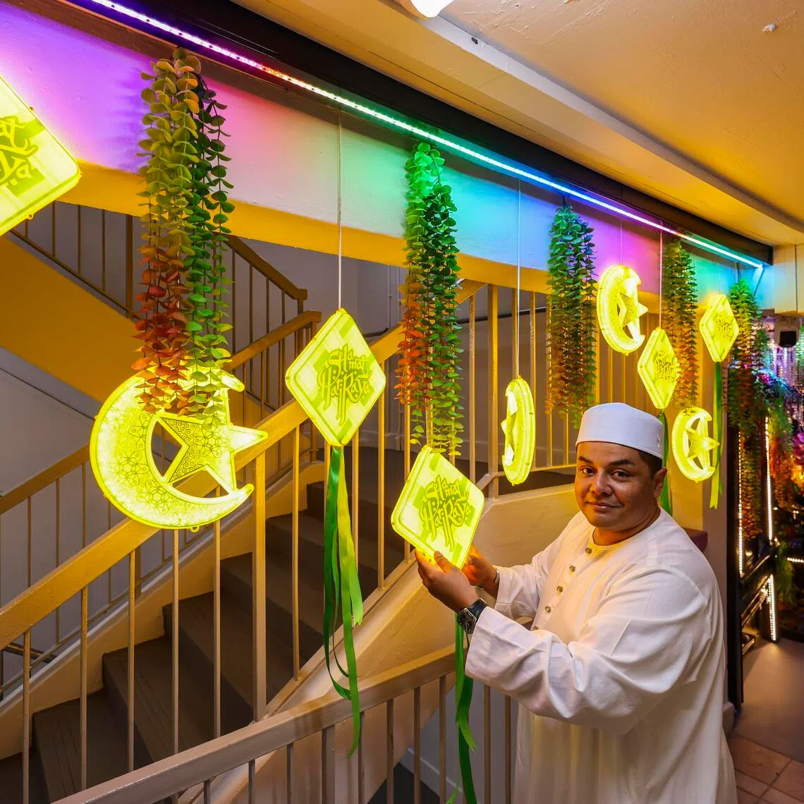 (PLS DO NOT USE PIX, PIX IS FOR PUBLICATION ON MARCH 21) Mr Ryan Qim (an alias), 49, a chef, adjusting his Hari Raya decorations outside his flat in Beach Road on March 9, 2026. He began decorating his apartment six years ago after noticing that the festive spirit of Hari Raya seemed to be fading, and now creates a different theme each year. This year’s “Garden Raya” theme was inspired by his love for flowers and the floral displays at Gardens by the Bay. Though a chef by profession, Mr Qim picked up interior design as a passion about 15 years ago and now does freelance consulting work on the side. His elaborate decorations have drawn the attention of neighbours, who often stop to take photos and compliment his work. His desire to decorate stems from childhood memories of his family adorning their home during Hari Raya, which brought relatives and neighbours together. To Mr Qim, Hari Raya is a time for family bonding, and he hopes his decorations help share the festive spirit with others. ST PHOTO: BRIAN TEO  