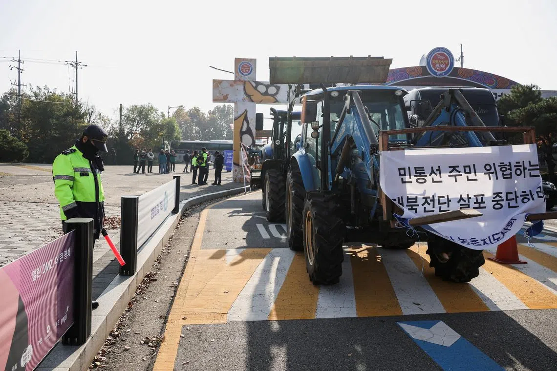 FILE PHOTO: A policeman stands near tractors of farmers who live in villages near the Military Demarcation Line (MDL), inside the demilitarised zone separating the two Koreas, as the farmers take part in a protest against the launch of anti-North Korean leaflets which are planned to be sent today by a group representing families of South Korean abductees, in Paju, South Korea, Ocotber 31, 2024. REUTERS/Kim Hong-Ji/File Photo