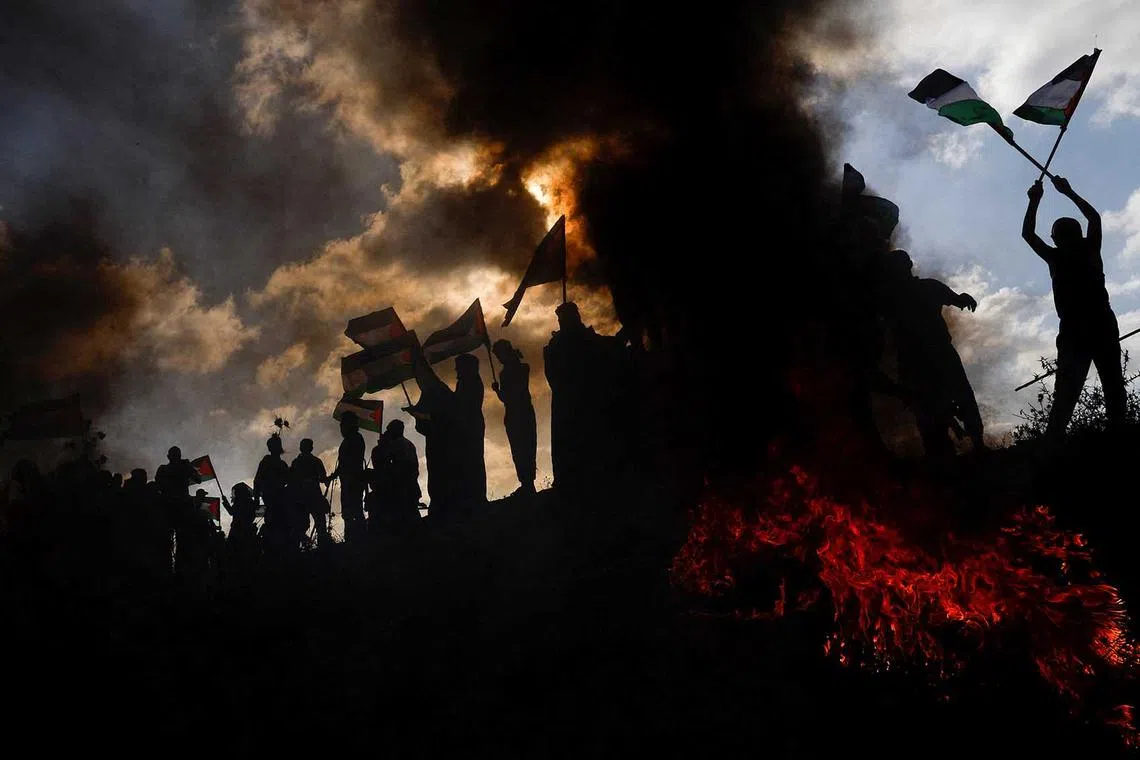 Palestinians taking part in a protest against the holding of the annual flag march in Jerusalem that marks Jerusalem Day, at the Israel-Gaza border fence east of Gaza City on May 18.