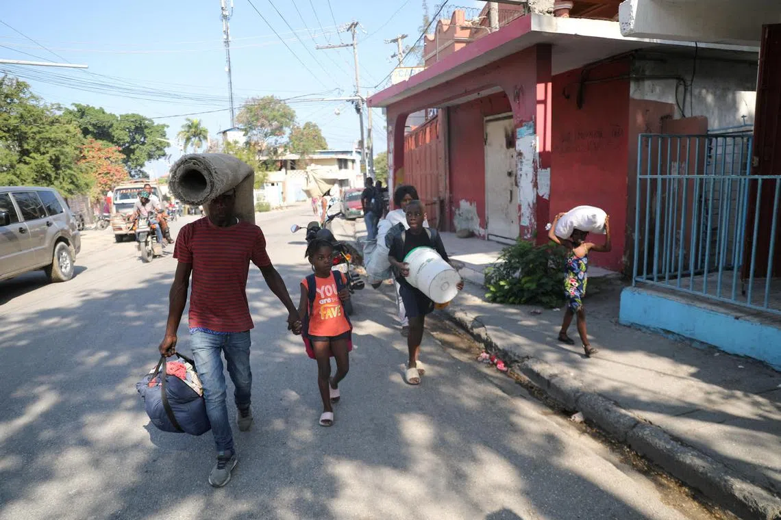 People fleeing from violence around their homes walk towards a shelter with their belongings in Port-au-Prince, Haiti.