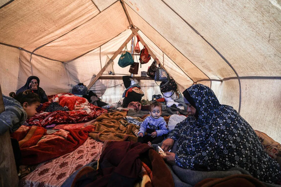 Members of a displaced Palestinian family sit inside a tent at a makeshift camp in Rafah set up by people who fled the ongoing battles between Israel and Hamas militants.