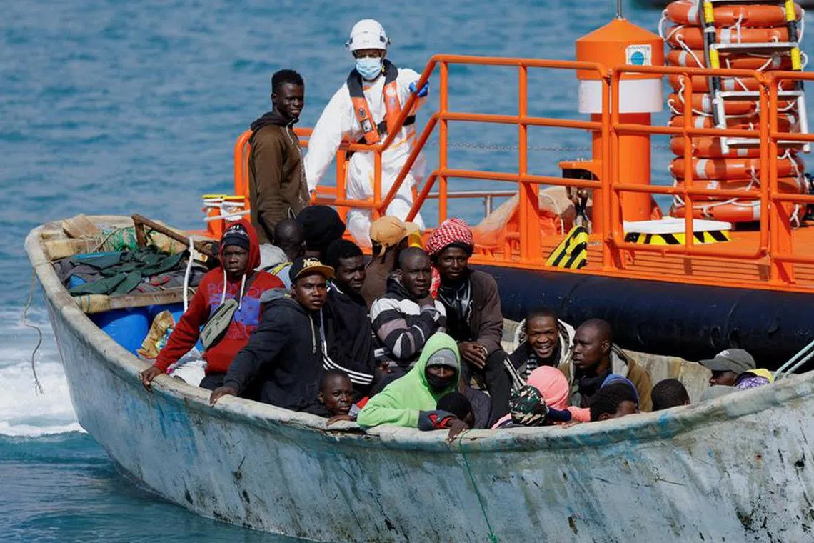 FILE PHOTO: A group of migrants wait to disembark from a wooden boat after being rescued by a Spanish coast guard vessel in the port of Arguineguin, on the island of Gran Canaria, Spain, January 18, 2024. REUTERS/Borja Suarez/File Photo