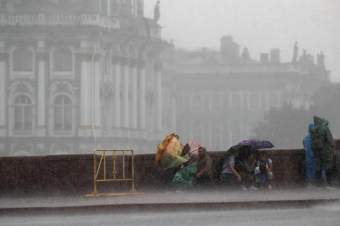 epa11490386 People sit under umbrellas during rainfall on the Neva River embankment in St. Petersburg, Russia, 21 July 2024. The temperature reached 22 degrees Celsius in Russia's second largest city.  EPA-EFE/ANATOLY MALTSEV