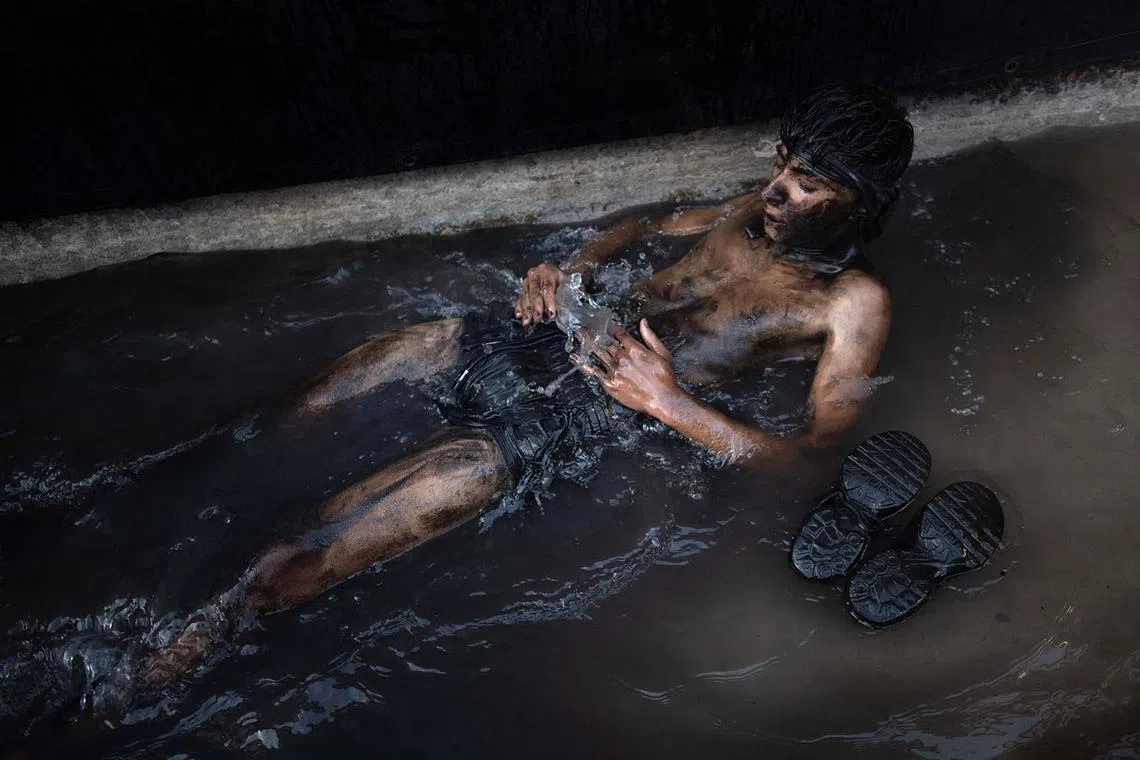 A reveller covered in black grease washes himself in a pool of water during the traditional Cascamorras festival, in Baza, near Granada, on September 6, 2025. Every September 6 a villager from Guadix, performing the "Cascamorras" oddball character, walks three kilometres to the village of Baza to stage an attempt to recapture a statue of the Pieta virgin before returning to Guadix, after three days, where he will be punished by locals for his failure. (Photo by JORGE GUERRERO / AFP)