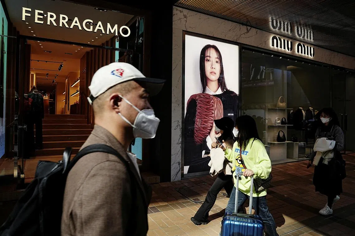 Shoppers walk past luxury stores at Tsim Sha Tsui district in Hong Kong.