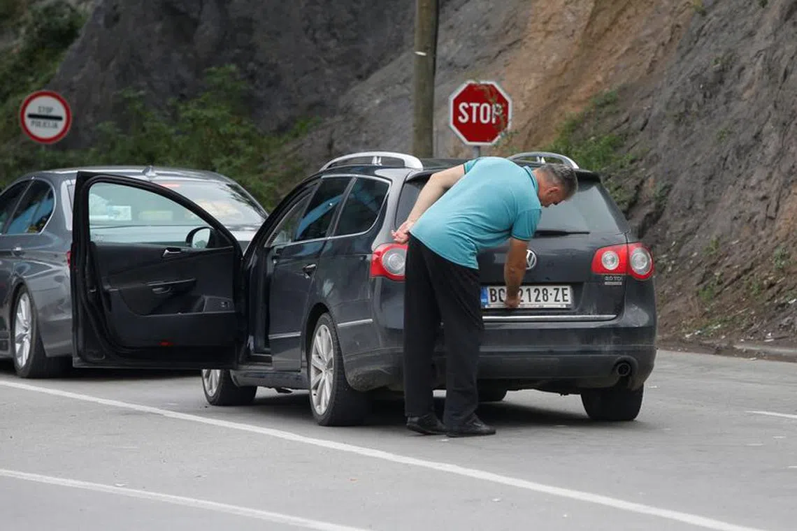 A driver removes a sticker covering the national markings on his car plates at the Jarinje border crossing, Kosovo September 1, 2022. REUTERS/Ognen Teofilovski/File Photo