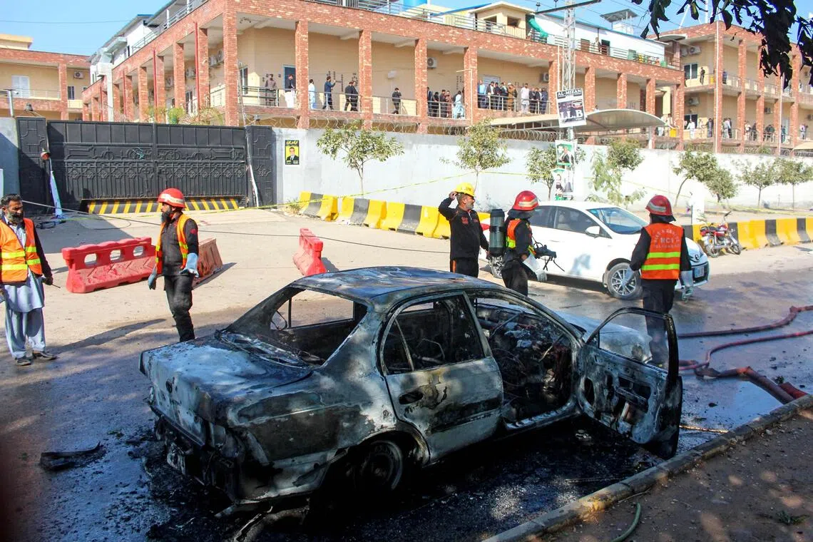 Firefighters douse a car at the suicide blast site in Islamabad on Nov 11.