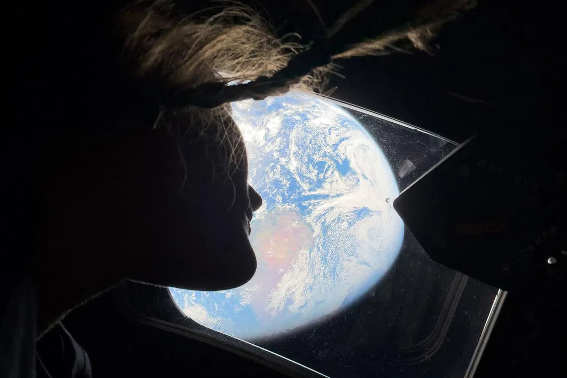 Artemis II mission specialist Christina Koch looking back at earth through the window of the Orion spacecraft on April 2.