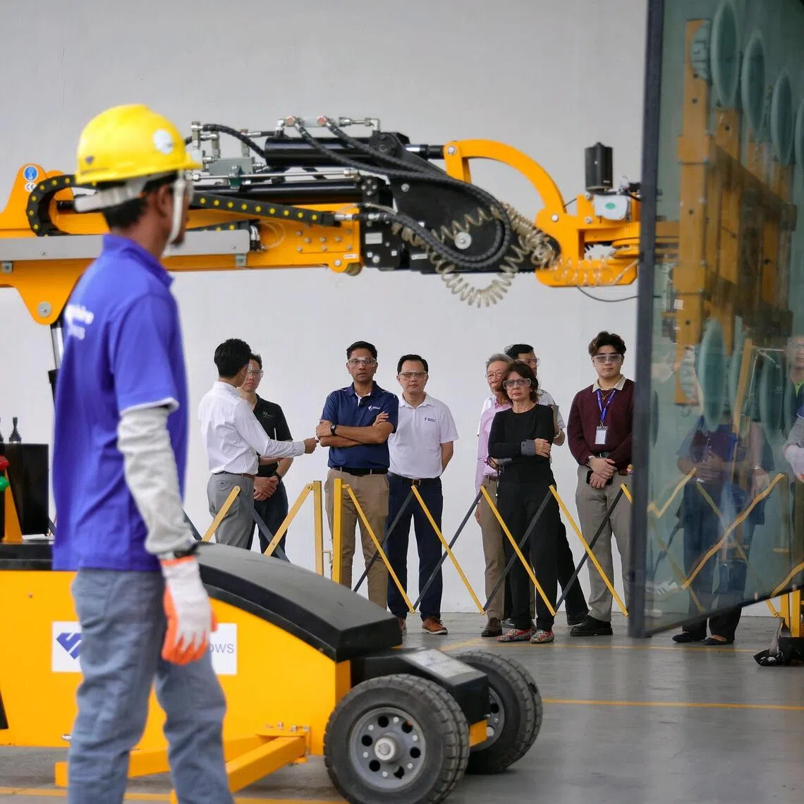 Minister of State for Ministry of Culture, Community and Youth and Ministry of Manpower Dinesh Vasu Dash (in dark blue top) looks on as workers (donning safety gloves) operate a glass lifting robot (which uses vacuum suction) during a tour of the factory and demonstration of good safety practices at Sapphire Windows in Loyang Drive on Sept 30, 2025. ST PHOTO: KEVIN LIM vcwsh30