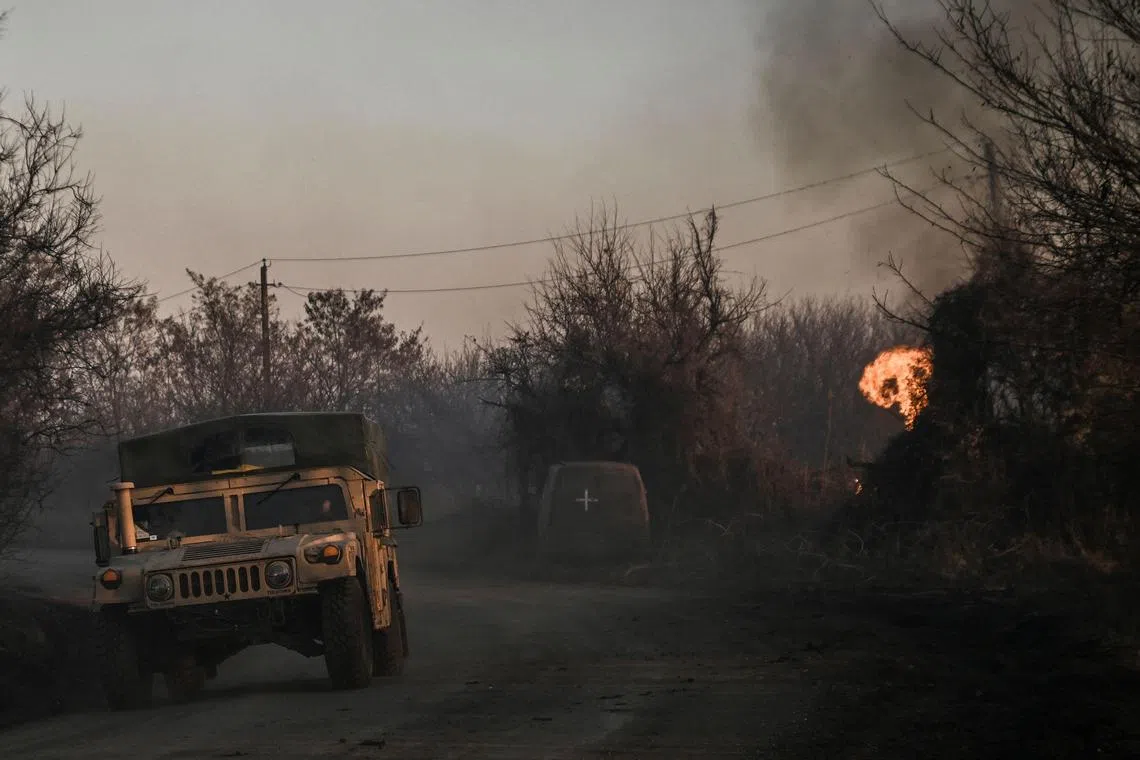 A Ukrainian military vehicle drives next to burning land, after a white phosphorus bomb exploded in the air, at the village of Chasiv Yar near Bakhmut, on March 14, 2023.