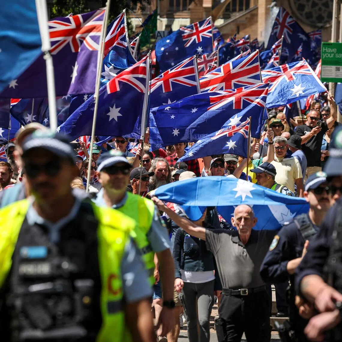 Protesters, watched by police, participate in the March for Australia rally in central Sydney on Oct 19, 2025. PHOTO: AFP