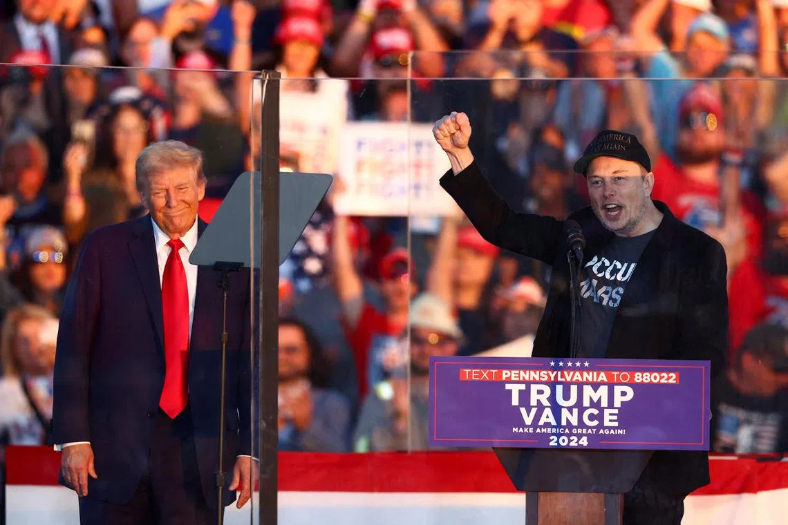 FILE PHOTO: Tesla CEO and X owner Elon Musk speaks as Republican presidential nominee and former U.S. president Donald Trump looks on during a rally at the site of the July assassination attempt against Trump, in Butler, Pennsylvania, U.S., October 5, 2024. REUTERS/Carlos Barria/File Photo