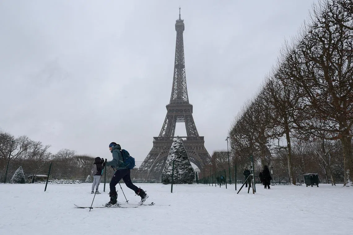 A woman skis on the snow-covered grounds near the Eiffel Tower in Paris as winter weather with snow and cold temperatures hits a part of the country, France, January 7, 2026. REUTERS/Gonzalo Fuentes