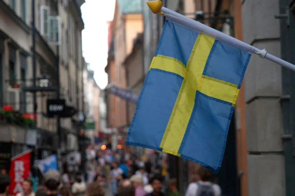 FILE PHOTO: A Swedish flag hangs outside a store on a busy street as visitors walk past in the background in the old town of Stockholm, Sweden, July 14, 2023 REUTERS/Tom Little/File Photo