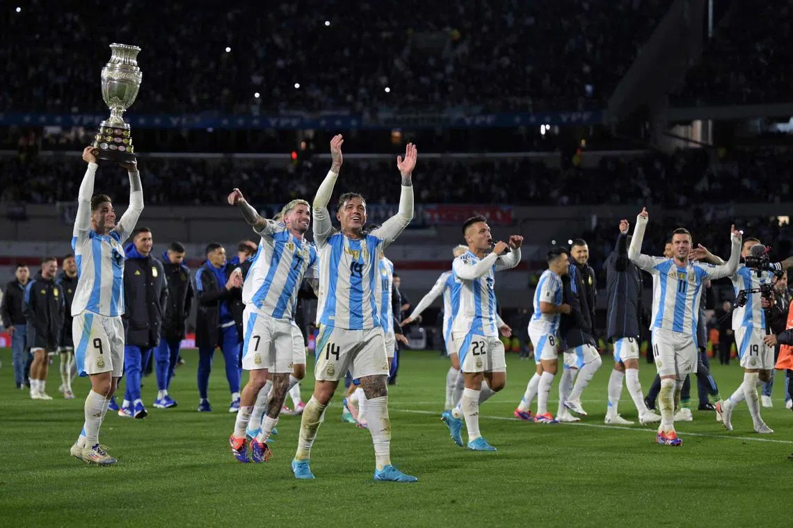 Argentina players celebrate their World Cup qualifying victory over Chile with a replica of the Copa America trophy.
