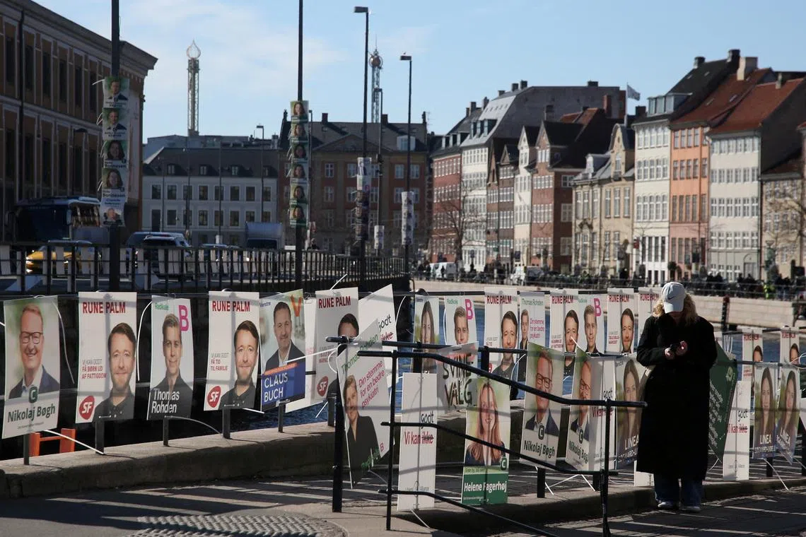 FILE PHOTO: A pedestrian stands next to posters for candidates in the upcoming Danish elections, in Copenhagen, Denmark, March 18, 2026. REUTERS/Tom Little/File Photo