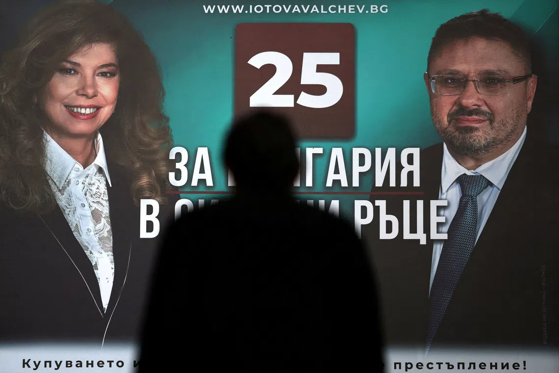 A person is silhouetted against an election billboard featuring Bulgarian presidential candidate and incumbent President Iliana Iotova and vice presidential candidate Kiril Valchev ahead of the country's presidential election on October 25, in Sofia, Bulgaria, October 22, 2026. REUTERS/Spasiyana Sergieva