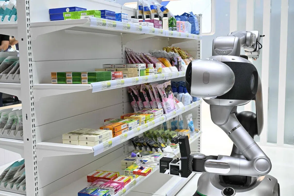 A Robbyant wheeled humanoid robot developed by Shanghai Ant Lingbo Technology Co., works at a drug store during the 2026 World Robot Conference in Beijing on Aug 20.