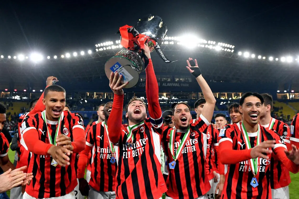 AC Milan's Davide Calabria celebrates with the trophy and teammates after winning the Italian Super Cup.