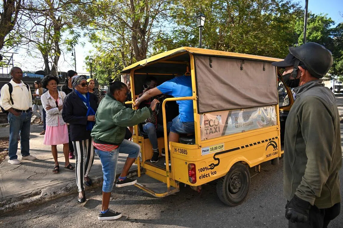 People line up to board an electric tricycle on a street in Havana, on Feb 13.