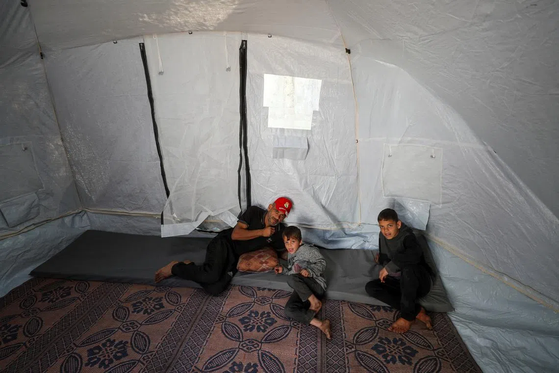 Displaced Palestinian man Khader Junaid and his children stay in their tent as the wait to flee after the Israeli army issued evacuation orders for a number of neighborhoods, following heavy Israeli strikes, in Jabalia in the northern Gaza Strip March 19, 2025. REUTERS/Mahmoud Issa