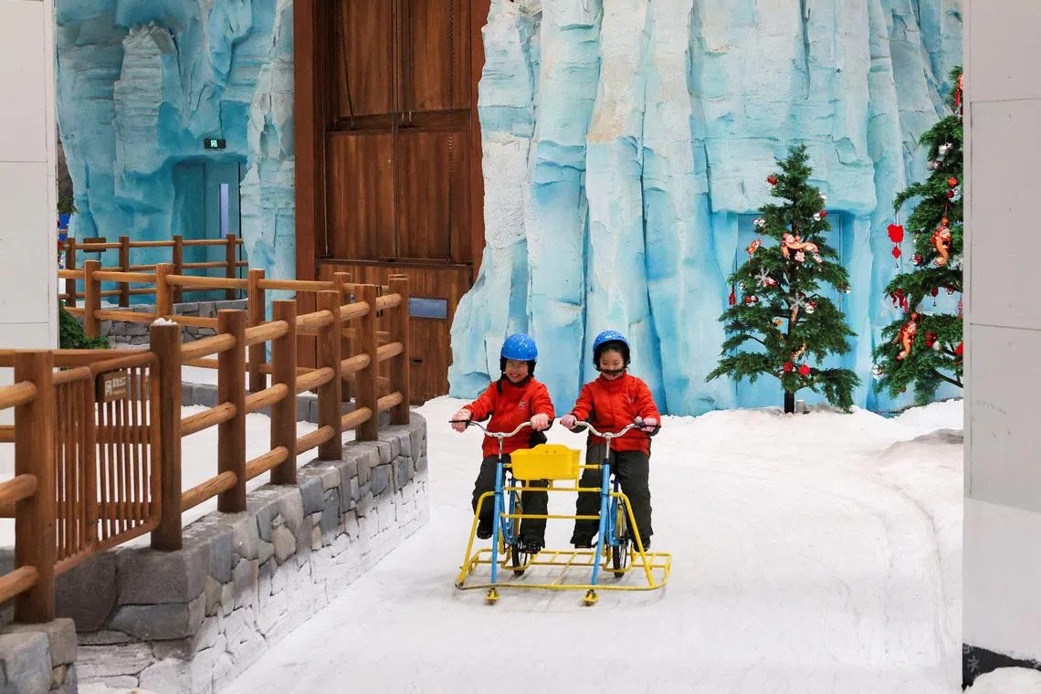 FILE PHOTO: Children ride a snow bicycle at Shanghai L+SNOW Indoor Skiing Theme Resort amid an orange alert for heat in Shanghai, China August 28, 2025.
