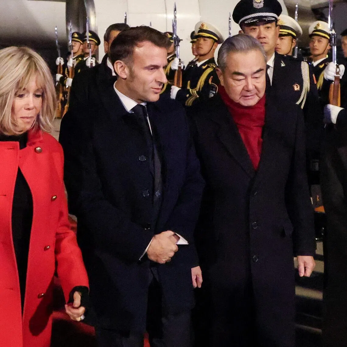 China's Foreign Minister Wang Yi receives France's President Emmanuel Macron and his wife Brigitte Macron upon their arrival at the Capital International Airport in Beijing, China, on Dec 3.