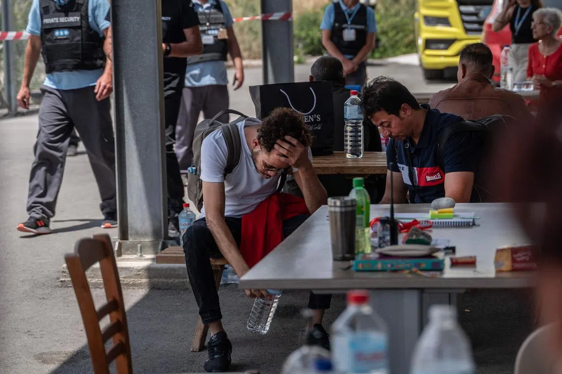 Family members of a missing person search for information, after shipwreck survivors are transferred to a migrant camp in Greece.