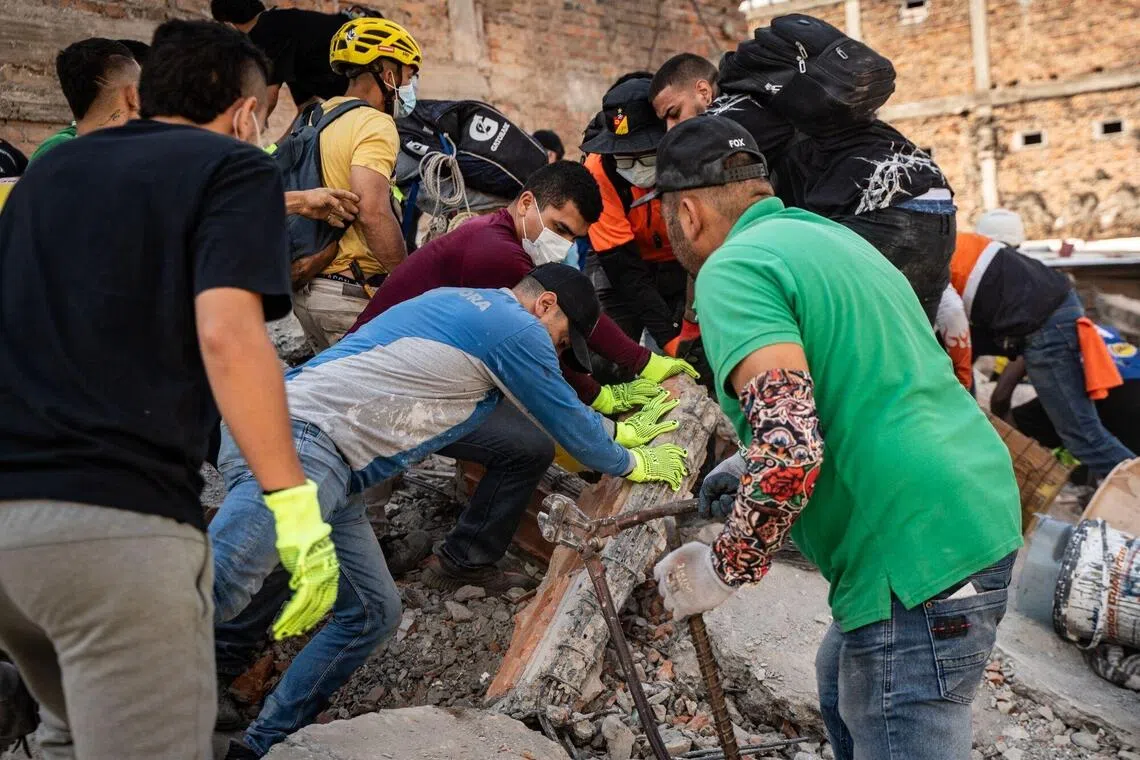 Rescue workers and volunteers clear debris following the earthquake in a bid to search for more survivors.