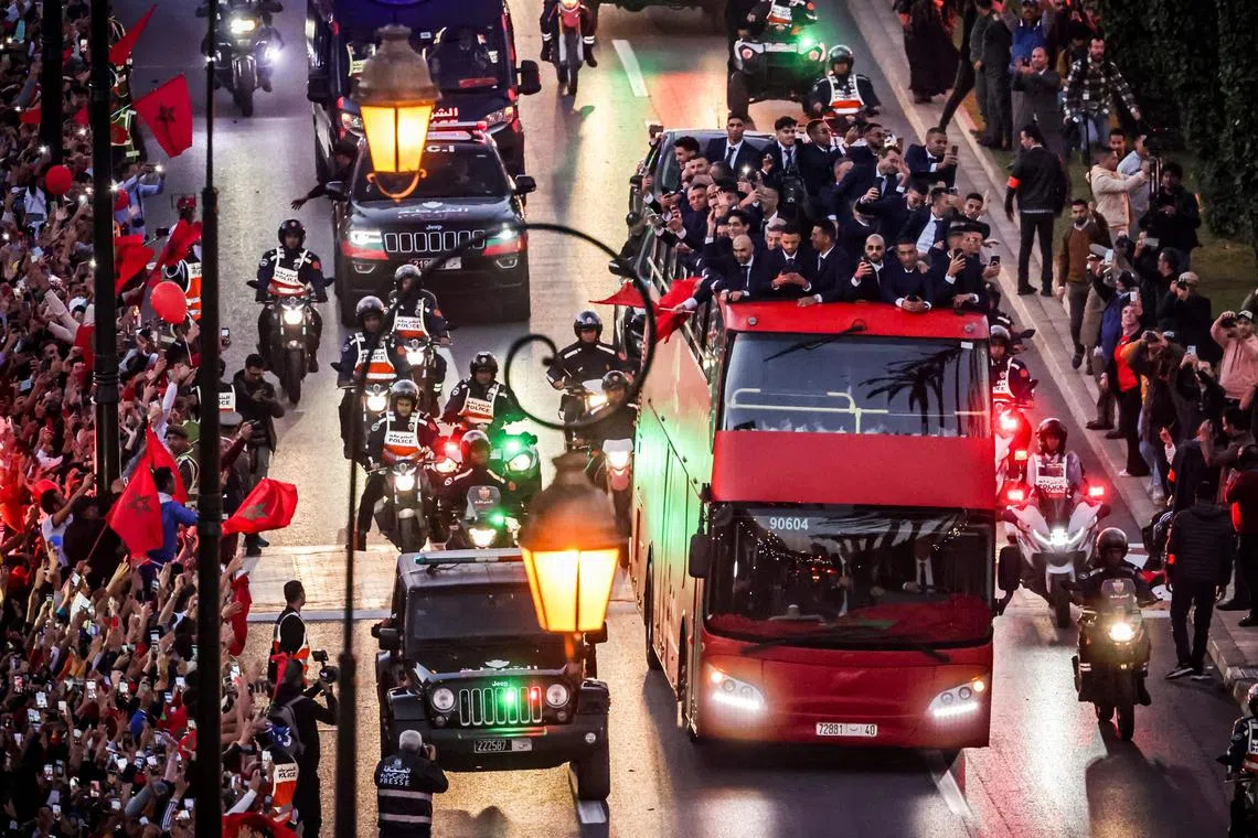 TOPSHOT - Supporters cheer as Morocco's national football team arrives to the center of the capital Rabat, on December 20, 2022, after the Qatar 2022 World Cup. (Photo by FADEL SENNA / AFP)