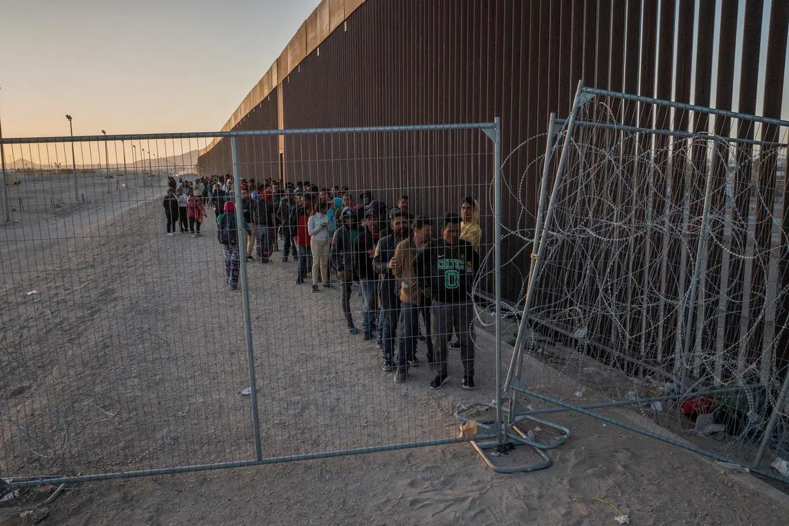 FILE PHOTO: A drone view show migrants as they line up against the border wall to surrender to immigration officials after breaching a razor wire laden fence along the bank of the Rio Grande river in El Paso, Texas, U.S., March 29, 2024.  REUTERS/Adrees Latif/File Photo