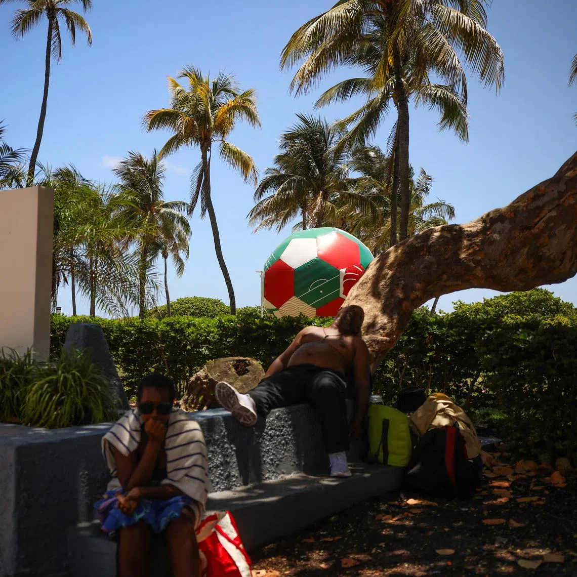An inflatable soccer ball sits on Lummus Park as a man sleeps under a shaded tree  amid a heat advisory in Miami Beach, Florida, U.S., June 17, 2026. REUTERS/Maria Alejandra Cardona