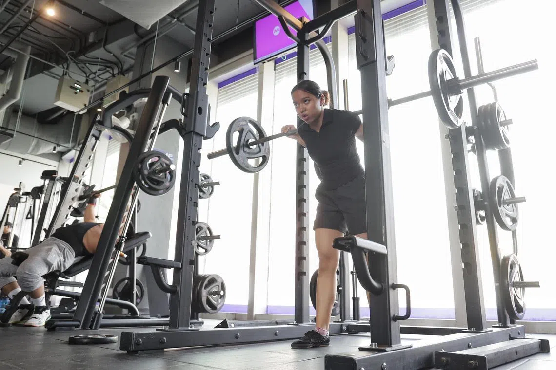 Ms Mhoo Waddy Ko, 18, doing squats with barbell at Anytime Fitness in Changi City Point on July 3, 2024. There is an increasing number of girls who are breaking stereotypes of how the female body should look like and are hitting the gym.