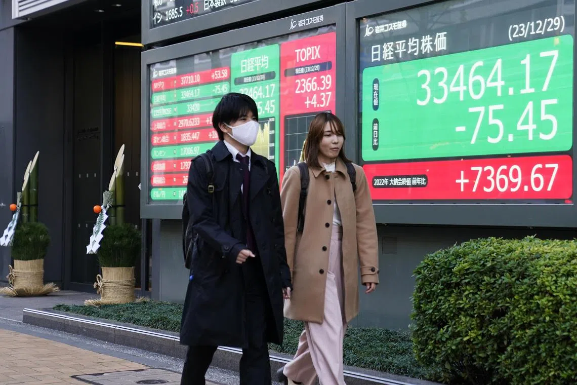 epa11047767 Pedestrians walk past a display showing closing information of the Nikkei Stock Average on the final trading day of the year 2023, at a securities company office, in Tokyo, Japan, 29 December 2023. The Tokyo stock benchmark closed down 75.45 points at 33,464.17. The Tokyo stock average closed its 2023 year's trade up 7369.67 points or 28 percent from a year earlier.  EPA-EFE/KIMIMASA MAYAMA