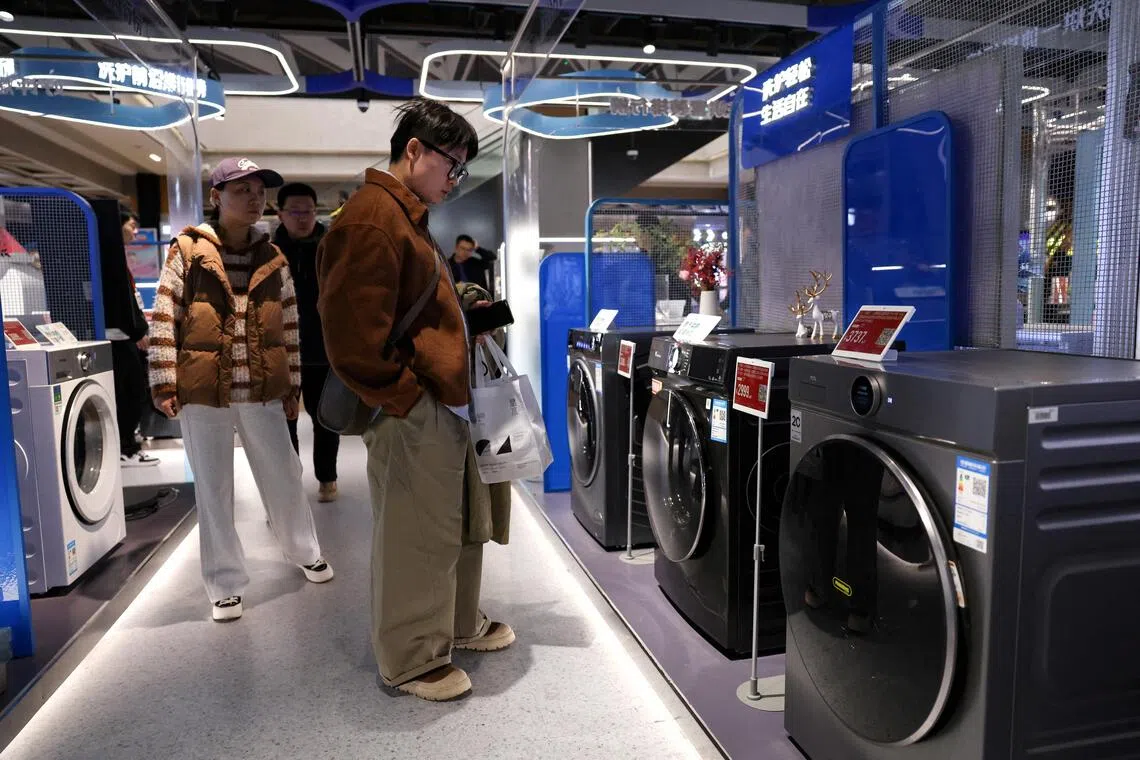 FILE PHOTO: Customers shop for a washing machine at a home appliance mall in Beijing, China October 19, 2025. REUTERS/Tingshu Wang/File Photo