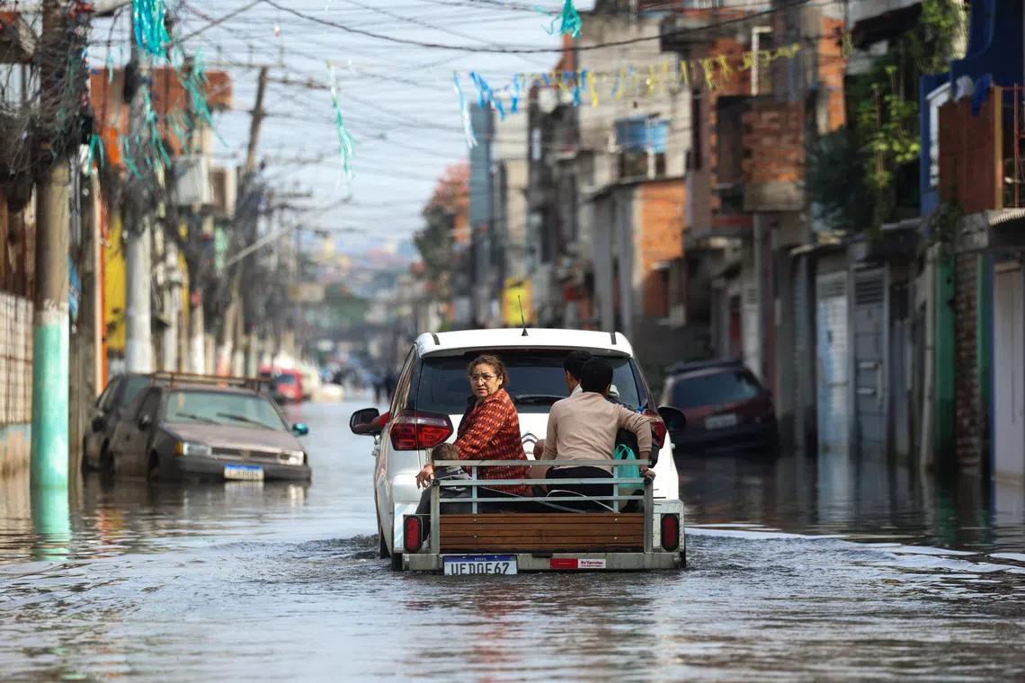 People ride on a trailer pulled by a car through a flooded street in the Jardim Pantanal neighborhood following heavy rains in Sao Paulo, Brazil, September 15, 2026. REUTERS/Tuane Fernandes TPX IMAGES OF THE DAY