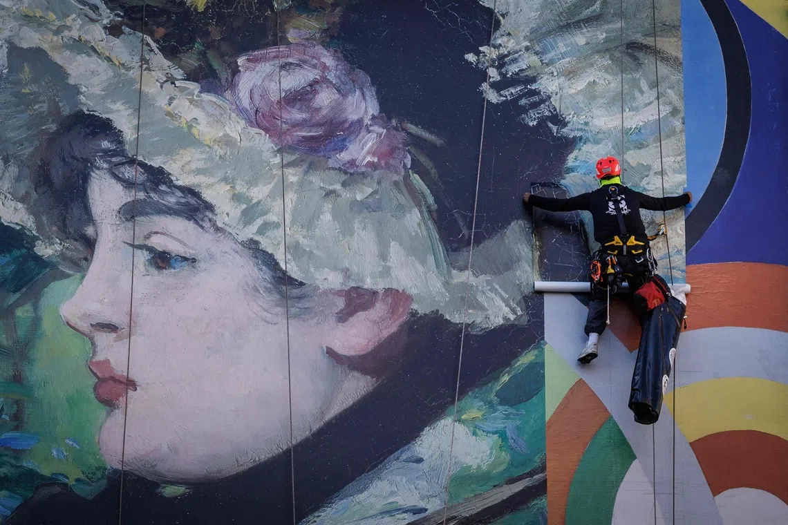 TOPSHOT - Workers install a reproduction of "Jeanne" by French painter Édouard Manet in Paris on September 21, 2026. (Photo by Simon WOHLFAHRT / AFP) / RESTRICTED TO EDITORIAL USE - MANDATORY MENTION OF THE ARTIST UPON PUBLICATION - TO ILLUSTRATE THE EVENT AS SPECIFIED IN THE CAPTION