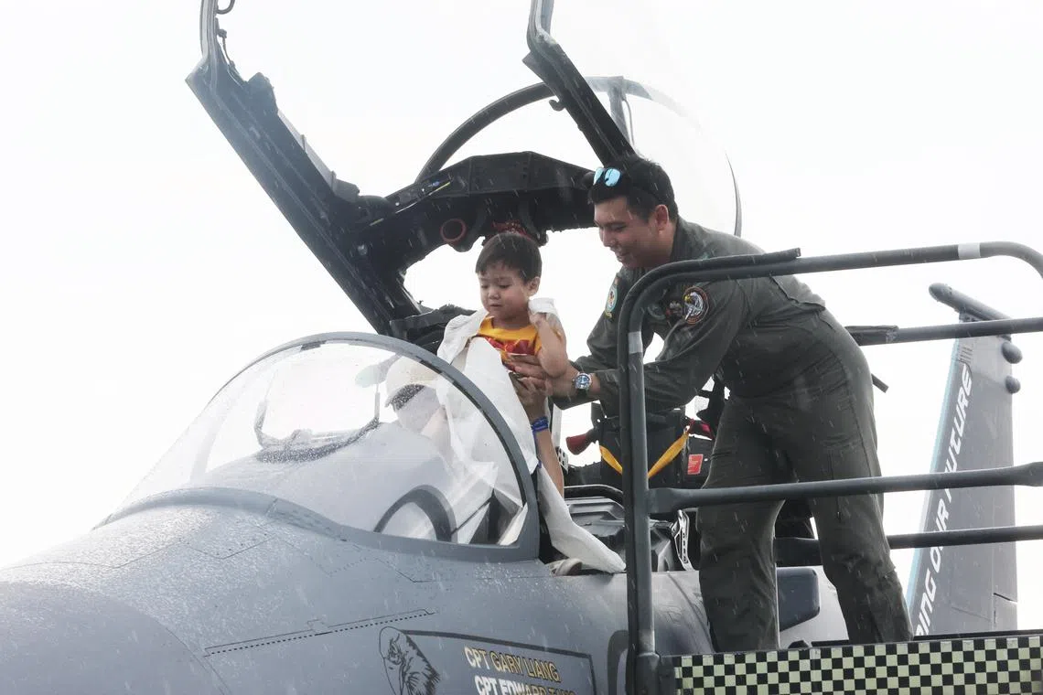 A child getting a lift into the cockpit of the F-15SG fighter aircraft at the RSAF Open House 2023 at the Paya Lebar Air Base on Sept 9.  