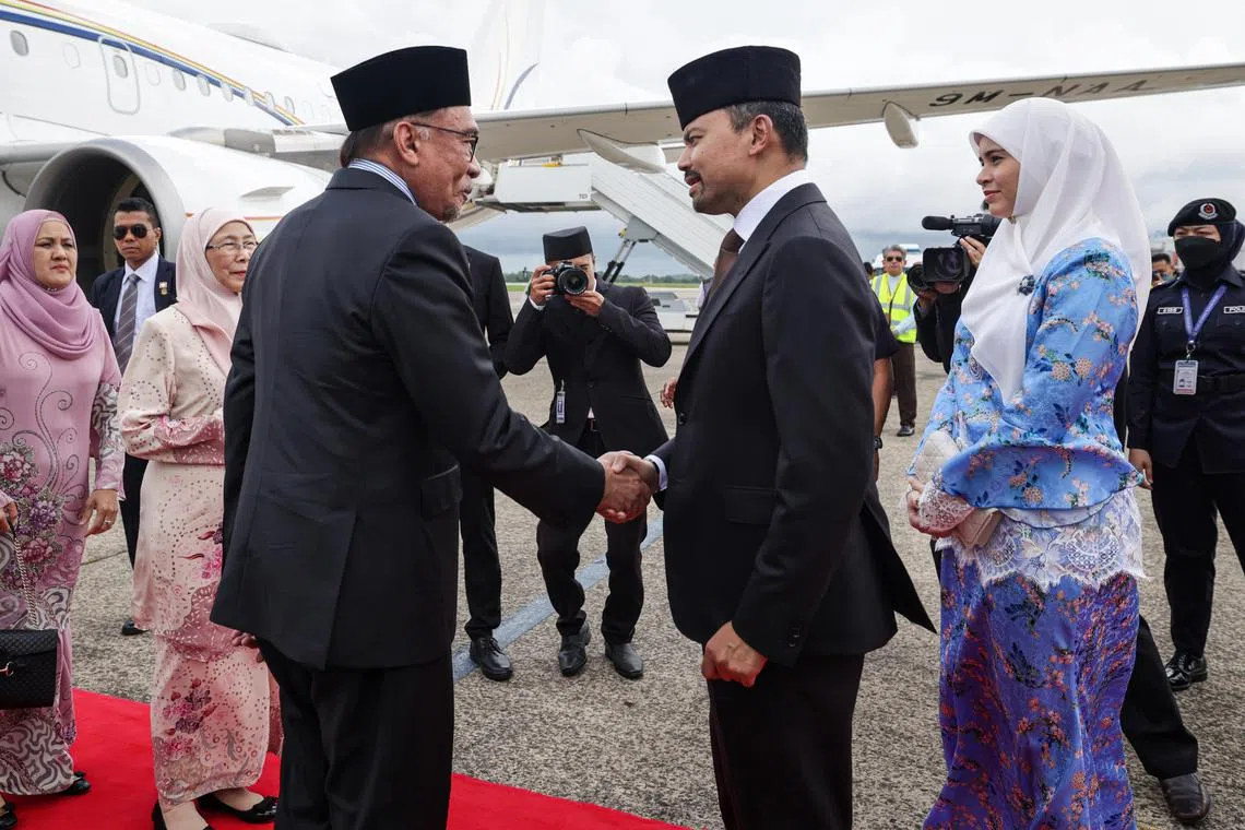 Malaysia's PM Anwar Ibrahim (left, foreground)  greeted by Brunei Crown Prince Al-Muhtadee Billah upon arriving in Brunei. 